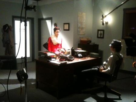 A man and woman sitting at a desk in front of a camera.