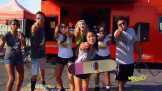 A group of people posing with skateboards in front of a red truck.