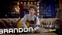 A boy sitting on the couch holding a guitar