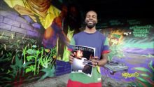A man with a colorful t shirt holding a book