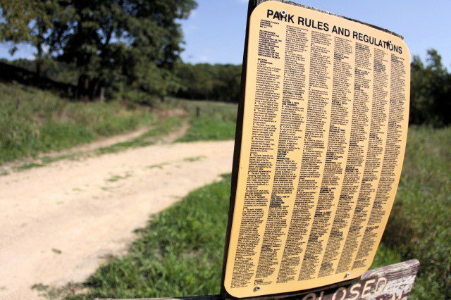 A sign on the side of a dirt road.