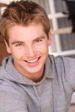 A young man smiling in a gray hoodie.