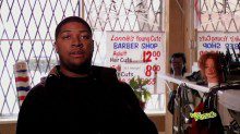 A man in a black outfit sitting in the barbershop
