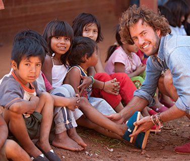A man kneeling in front of a group of children.
