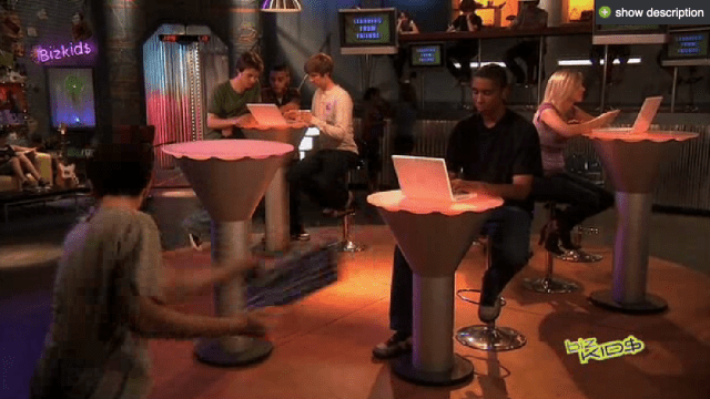 A group of people sitting around a table with laptops.