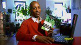 Man working at laptop and showing a book