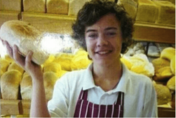 A young man holding a loaf of bread.