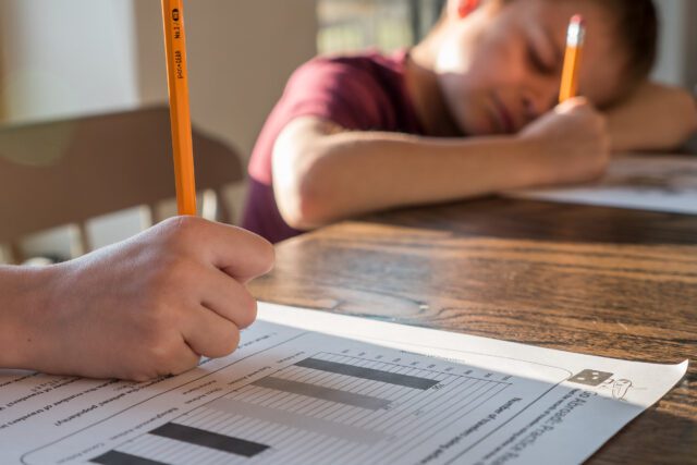 Close up shot of a boy writing with a pencil