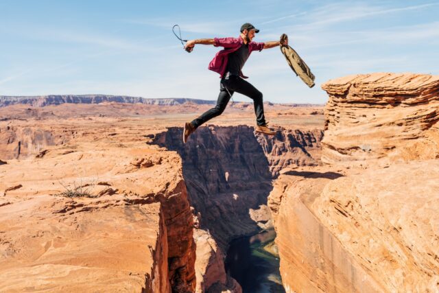 a man jumping from one side of the mountain to another