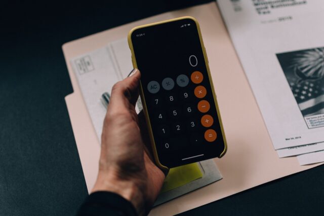 A man holding a phone with a calculator app opened