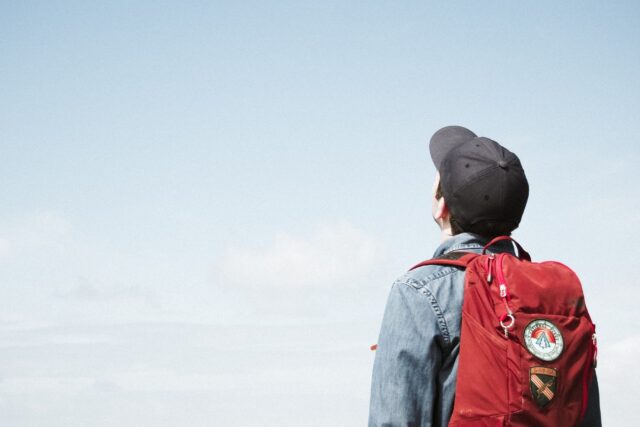 A man carrying a red color bag looking at the sky